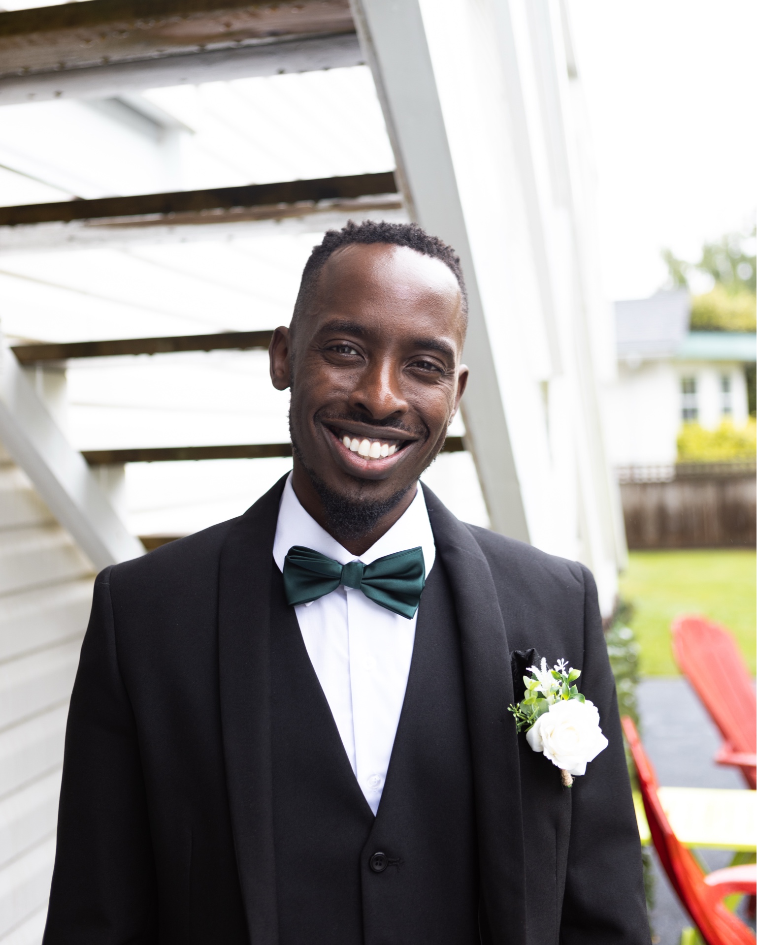 Portrait of a smiling man in formalwear with a green bow tie near an outdoor staircase