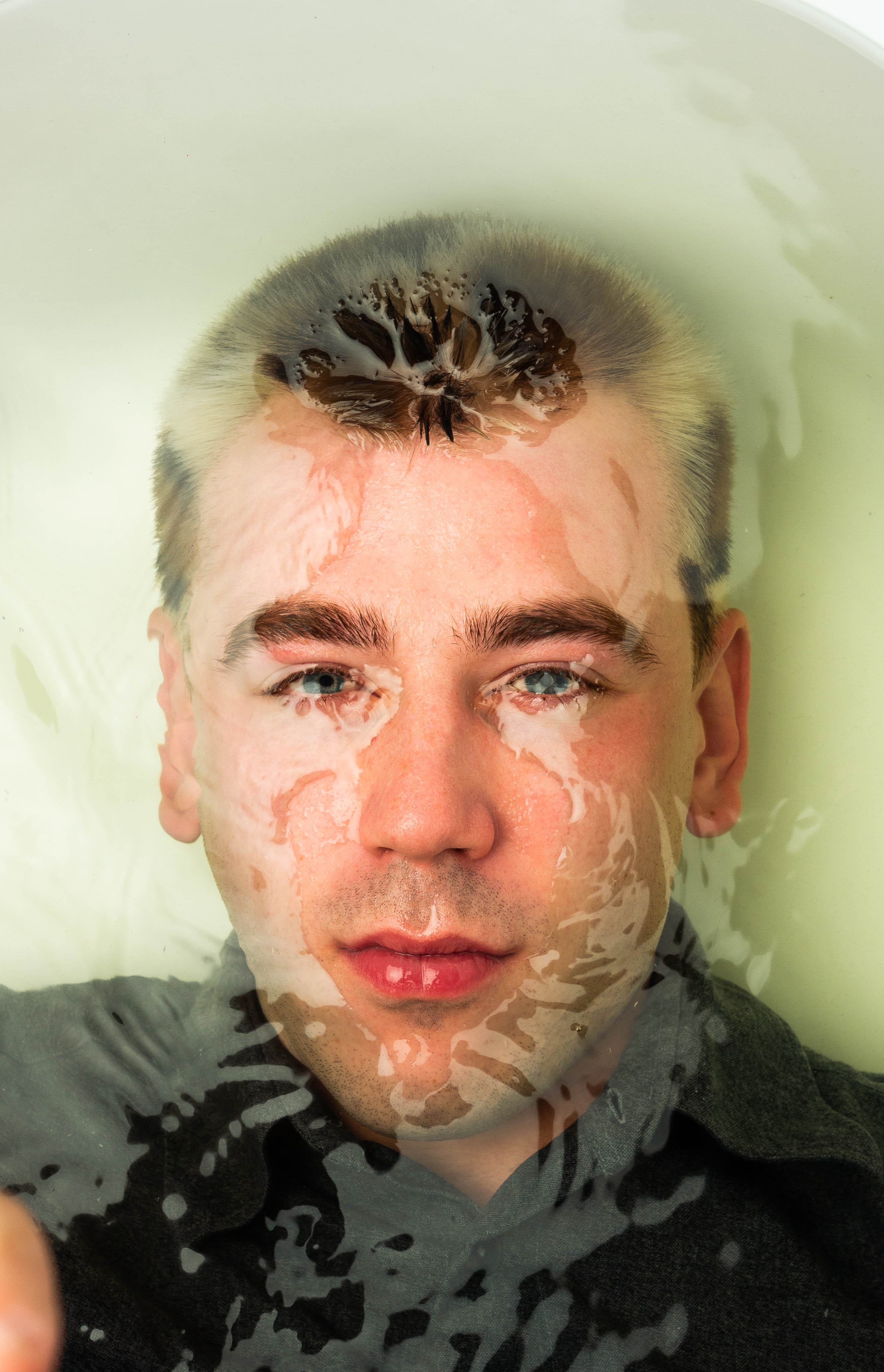 Creative portrait of a man partially submerged in water with abstract reflections across the face